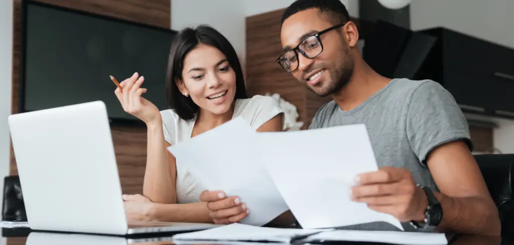 A couple comparing finance options in front of a laptop in their living room.