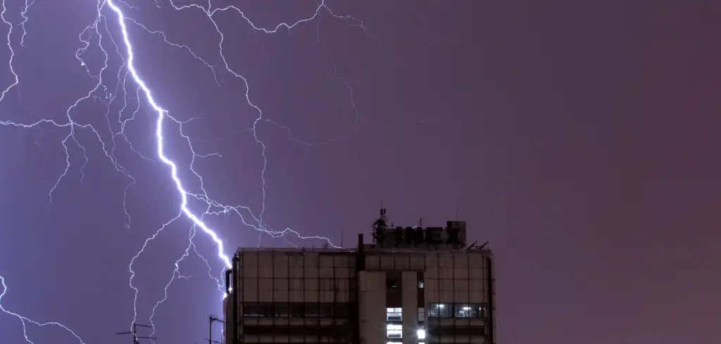 The lightning strikes the roof of an apartment building.
