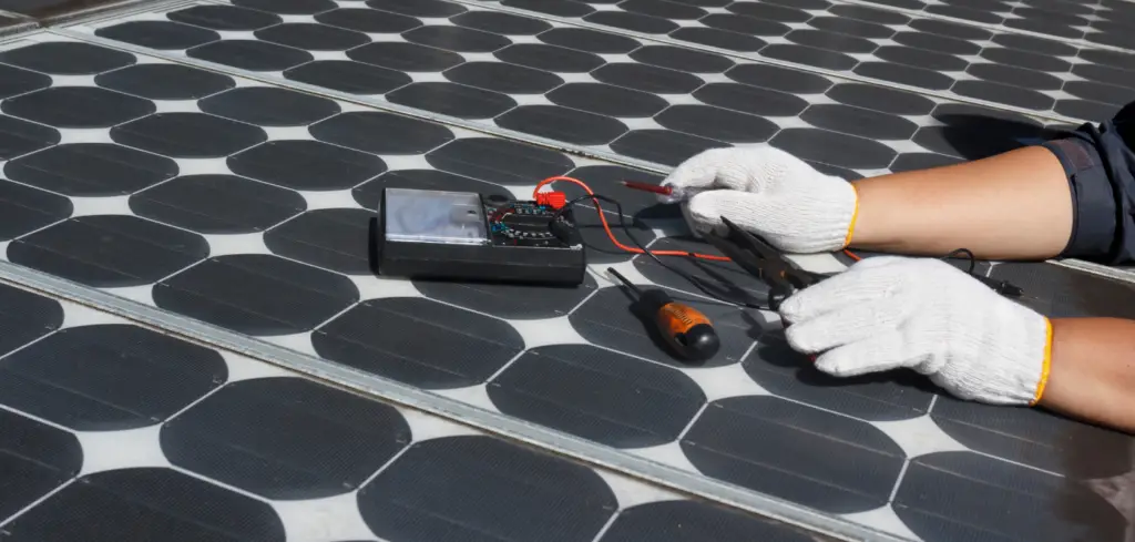 A solar technician with white gloves inspecting photovoltaic solar panels with a multimeter type of device.