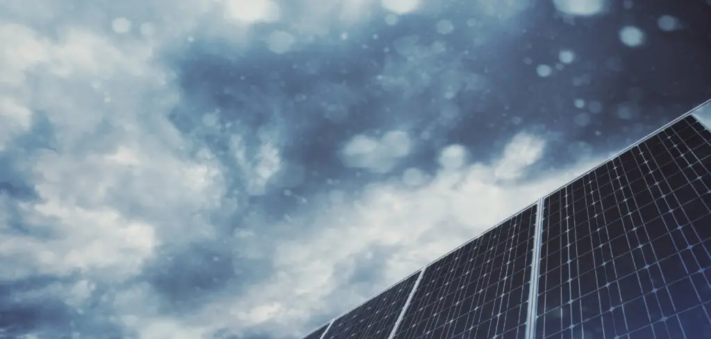 The upward angle of several solar panels and dark cloudy skies.