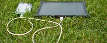 Solar trickle charger charging a phone outdoor on green grass