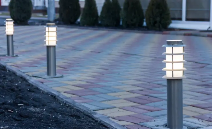 Three small solar path lights outdoors when it is getting dark.
