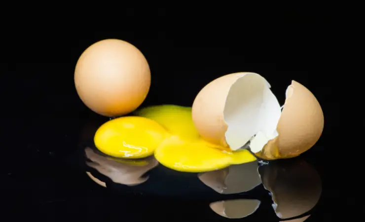 Broken egg with reflection on pure black background.