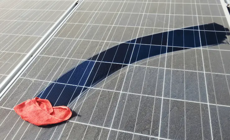 Microfibre cloth cleaning solar panel covered in thick layer of pollen.