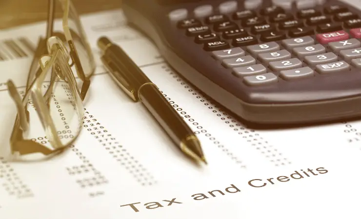 Image of a black pen, reading glasses and calculator on top of a tax and credit form.