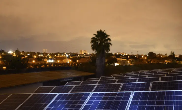 Solar panels on a house roof at night looking over the city.