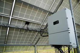 A large solar inverter underneath a solar panel installation.